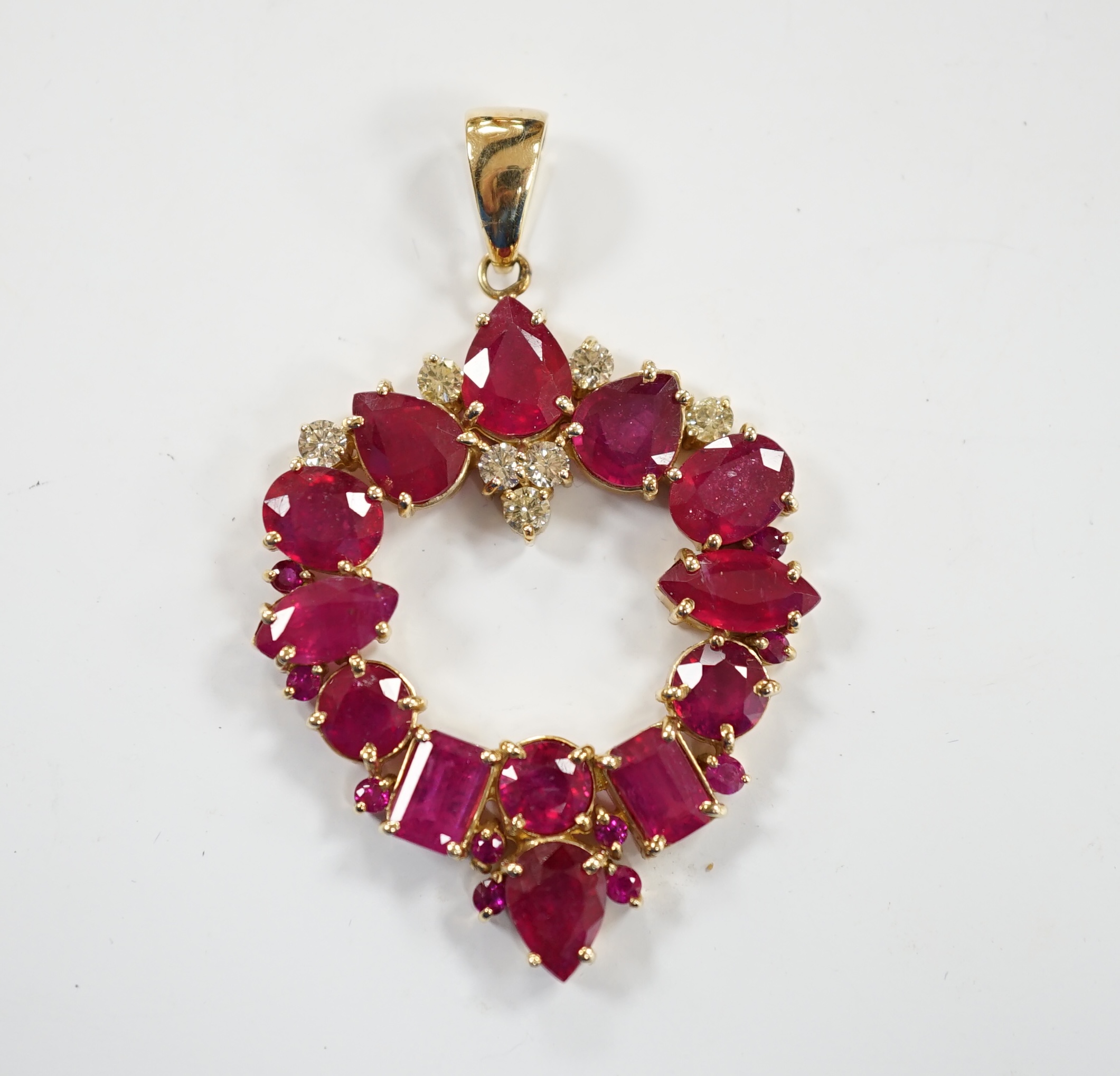 A modern 14k, ruby(treated) and diamond cluster set open work pendant, overall 52mm, gross weight 10.9 grams.